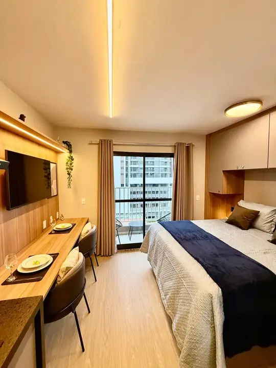 Studio da Wisehost em Santo Amaro: cama de casal arrumada, bancada e janela para a cidade