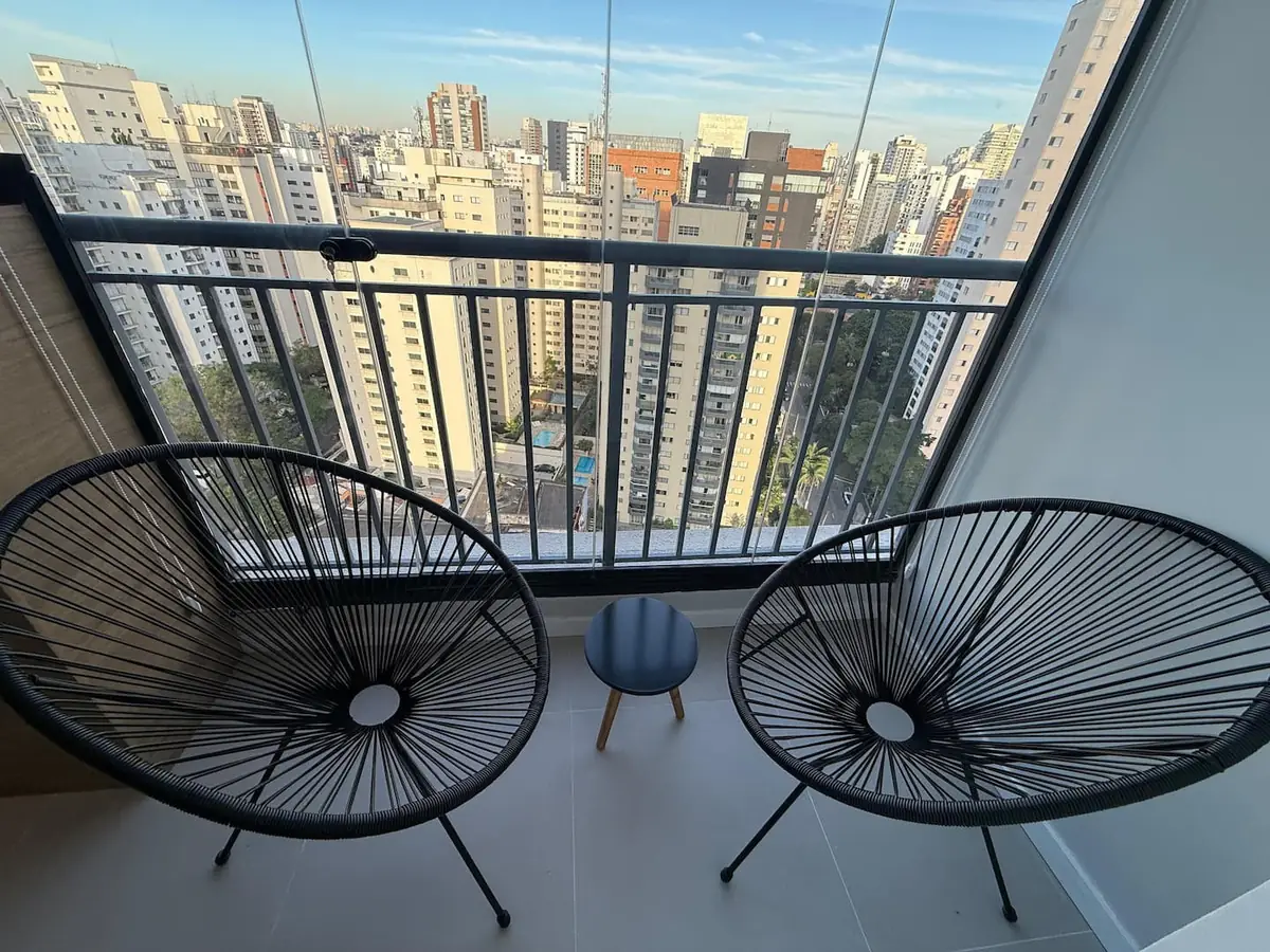 Varanda do studio com duas poltronas e vista para São Paulo